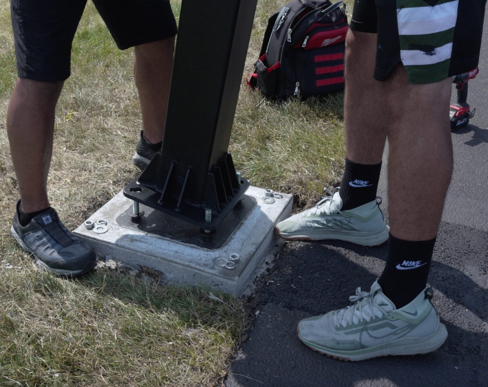 Anchor plate bolts at the base of an in-ground basketball pole set in concrete
