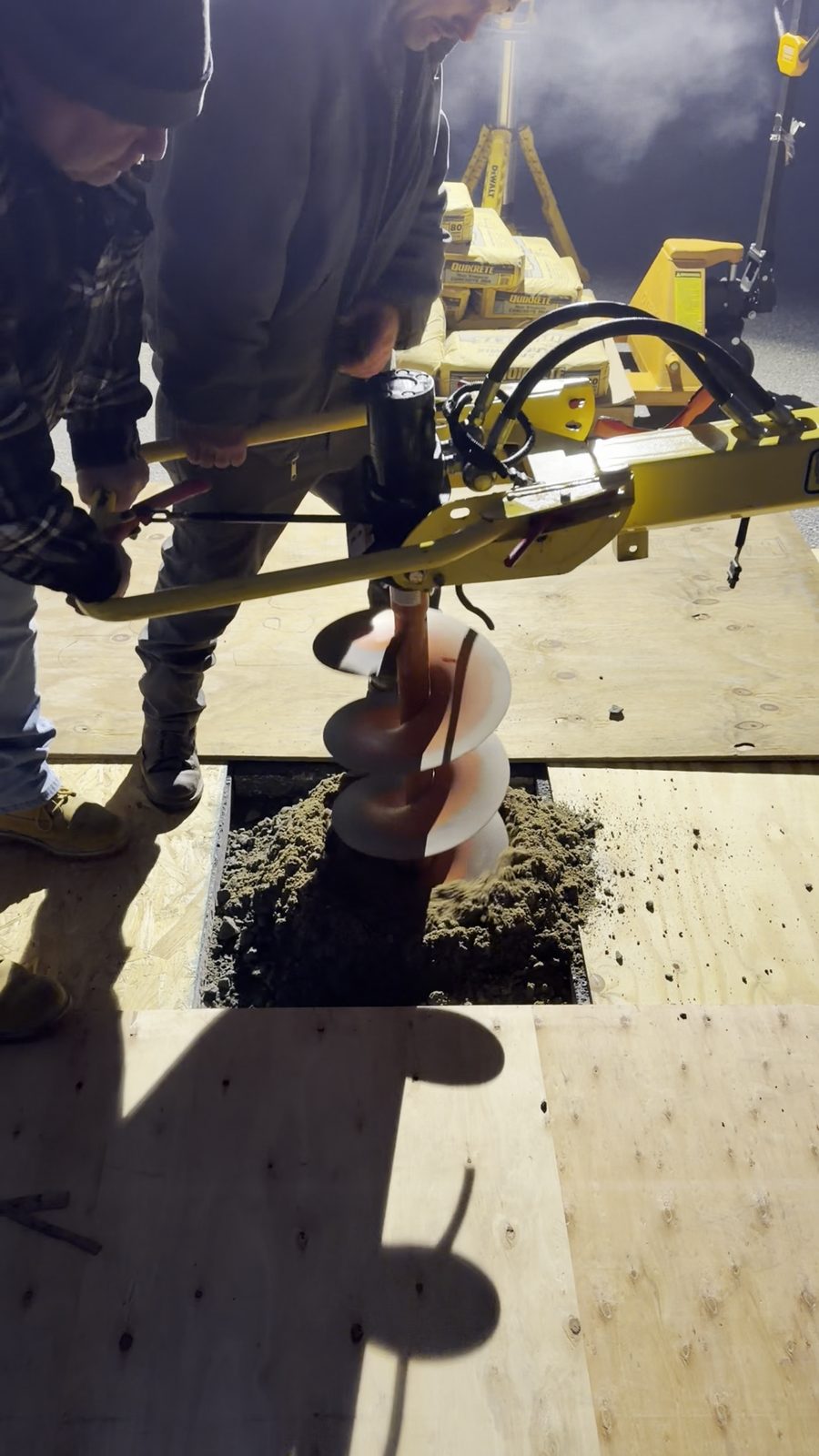Crew augering the footing hole for an in-ground hoop at night