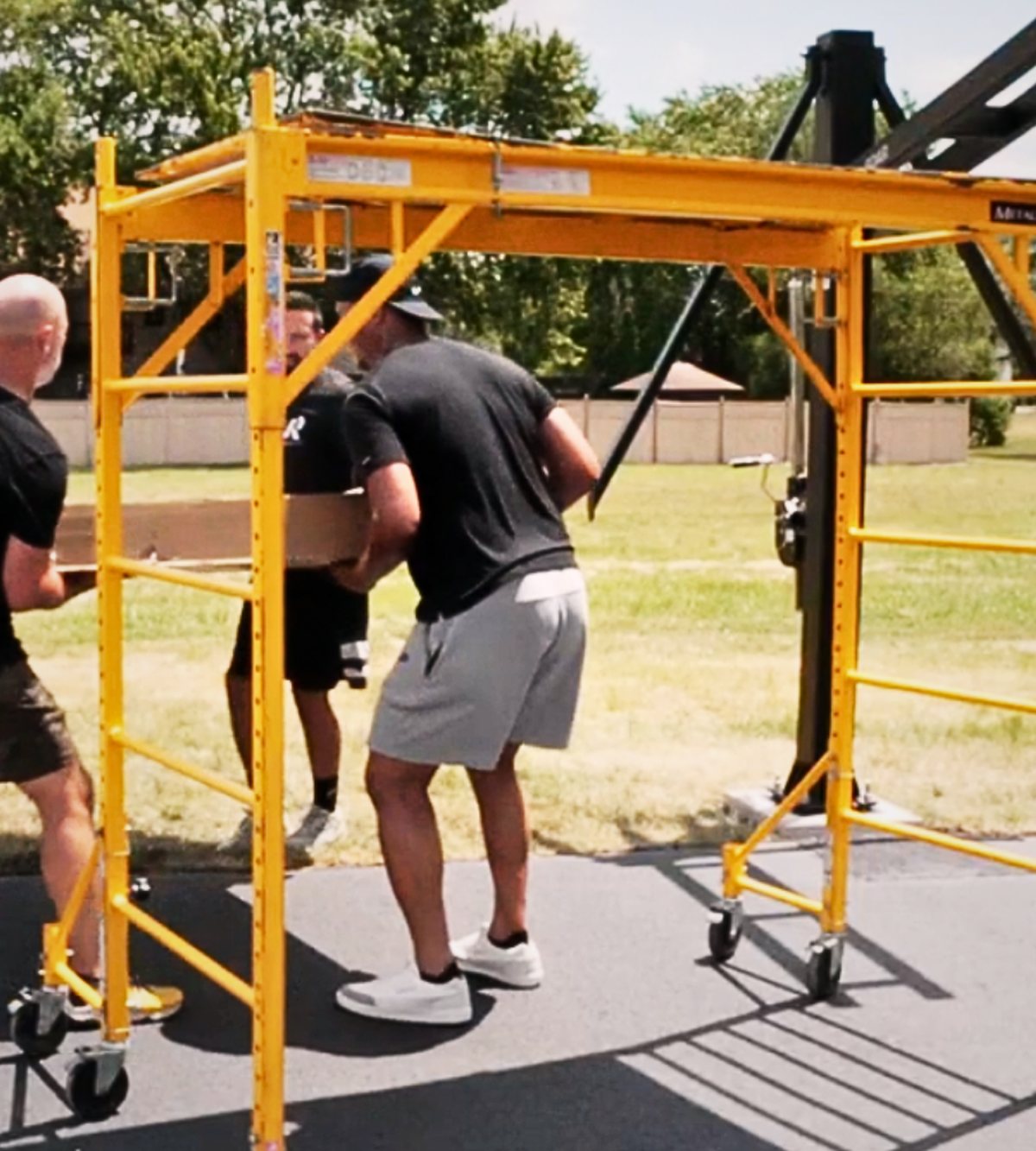 Play All Day crew assembling a basketball hoop system on a driveway