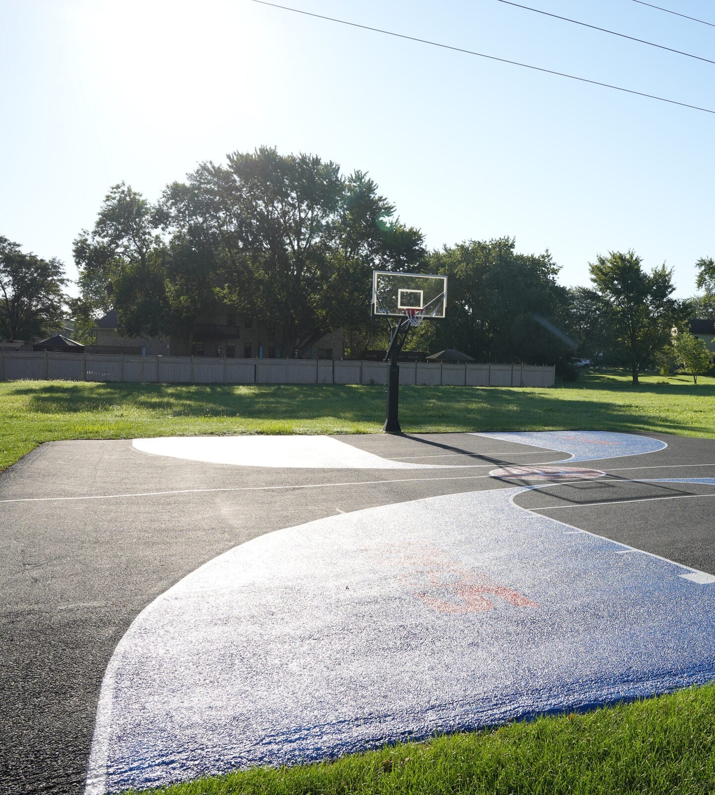 Wide view of a residential basketball court showing full playing surface and painted markings