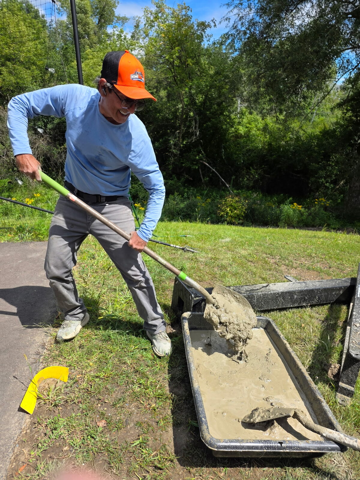 Installer mixing concrete for a basketball hoop footing