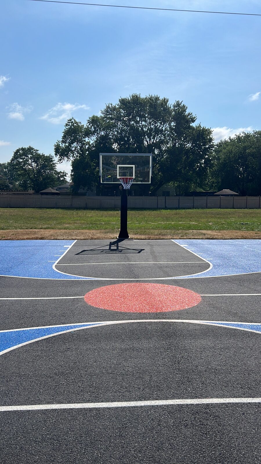 View from the baseline of a residential basketball court showing the full depth of the playing surface and painted key