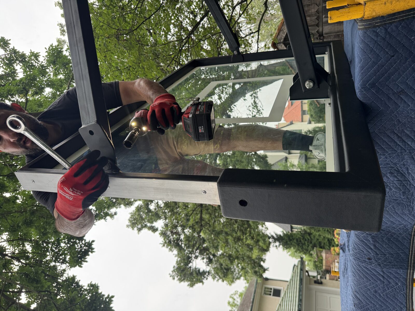 Hands checking the backboard mounting bracket hardware on a tempered glass backboard