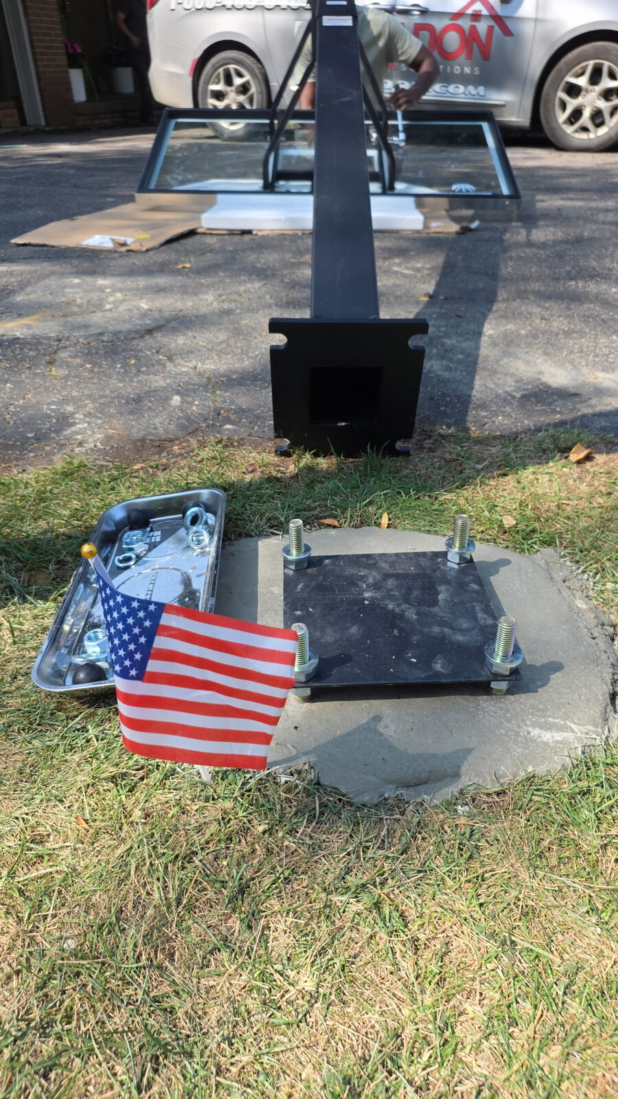Anchor plate and bolts set into a poured concrete footing beside a lawn