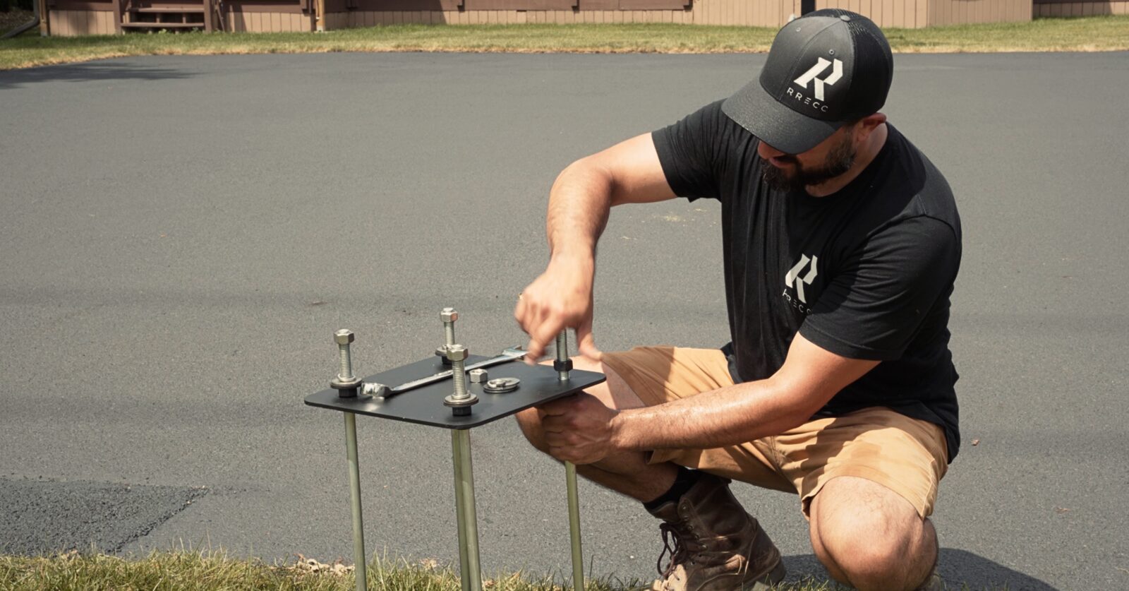 Installer preparing an anchor bolt kit on a paved surface before setting the footing