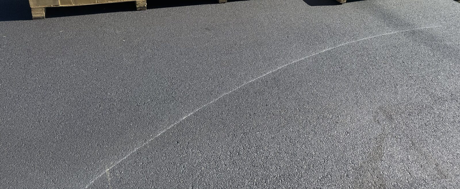 Smooth asphalt residential court surface showing consistent grade and a clean painted boundary line