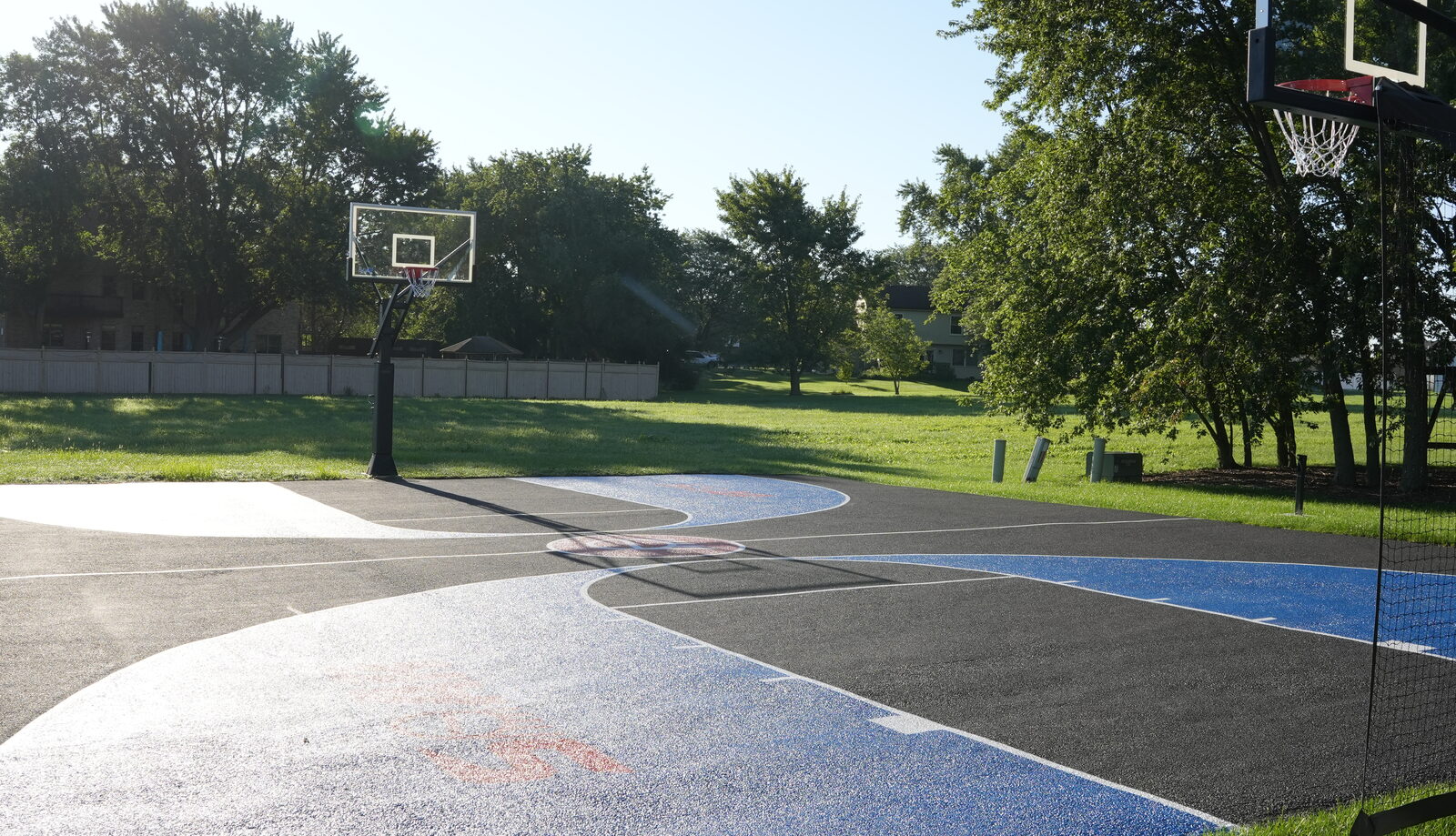 Finished residential basketball court with an in-ground hoop at the baseline