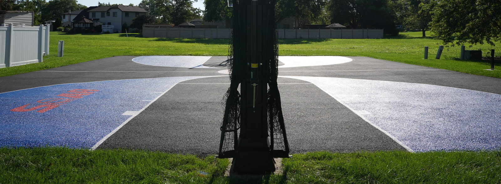Three-point arc and corner markings painted on a residential basketball court surface