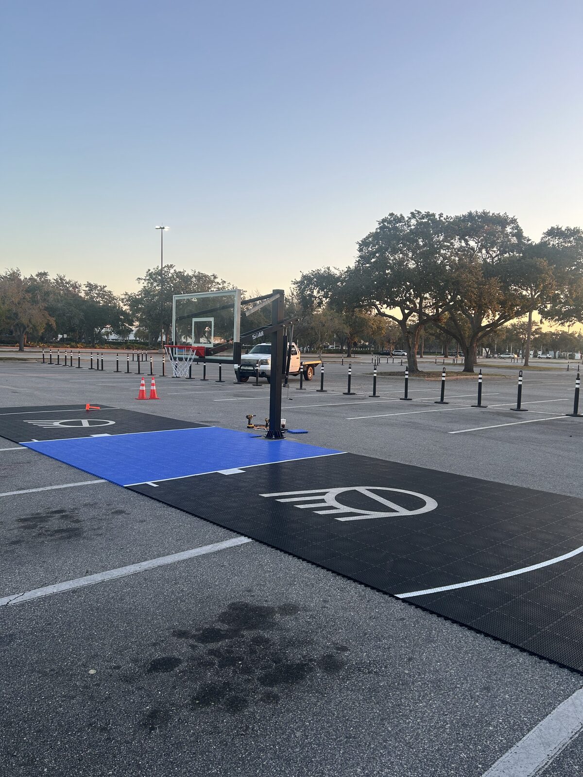 Residential basketball court at dusk with painted markings and an in-ground hoop