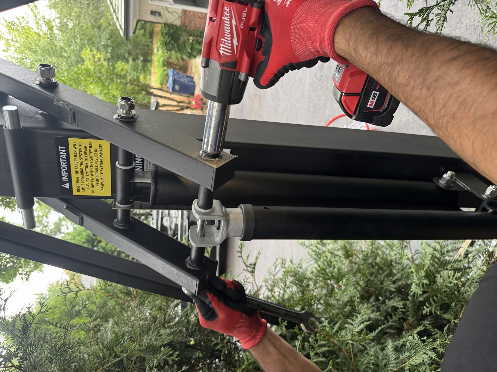 Installer tightening hardware on a basketball hoop extension arm with a power driver